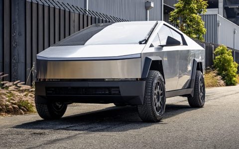 Tesla Cybertruck parked on an urban street featuring 50mm wheel spacers by Unplugged Performance, enhancing stance and stability. Close-up view highlighting the aggressive wheel offset and unique geometric design of the Cybertruck's exterior.